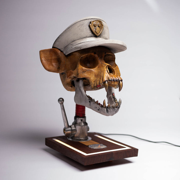Dead Chase sculpture: carved ash-wood skull with a concrete cap on a fire hose nozzle, seen from above at an angle