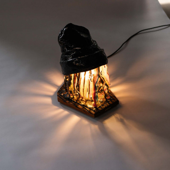 Melting Sahne sculpture glowing on a grey surface with the power cable visible