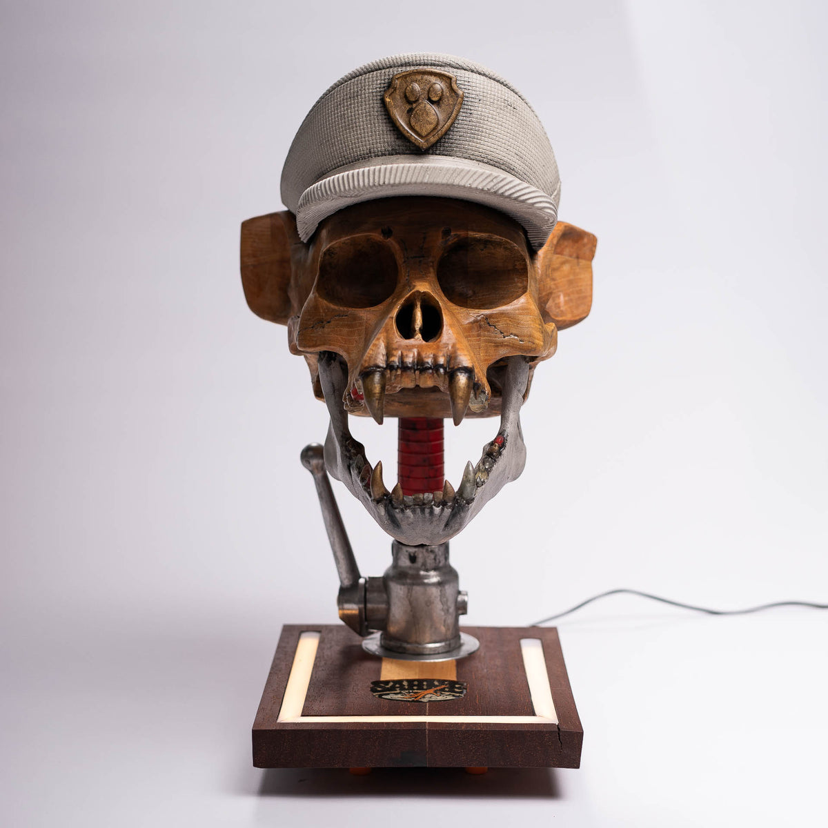 Dead Chase sculpture, front view: hand-carved ash-wood skull with concrete cap and open concrete-look jaw on a wooden base