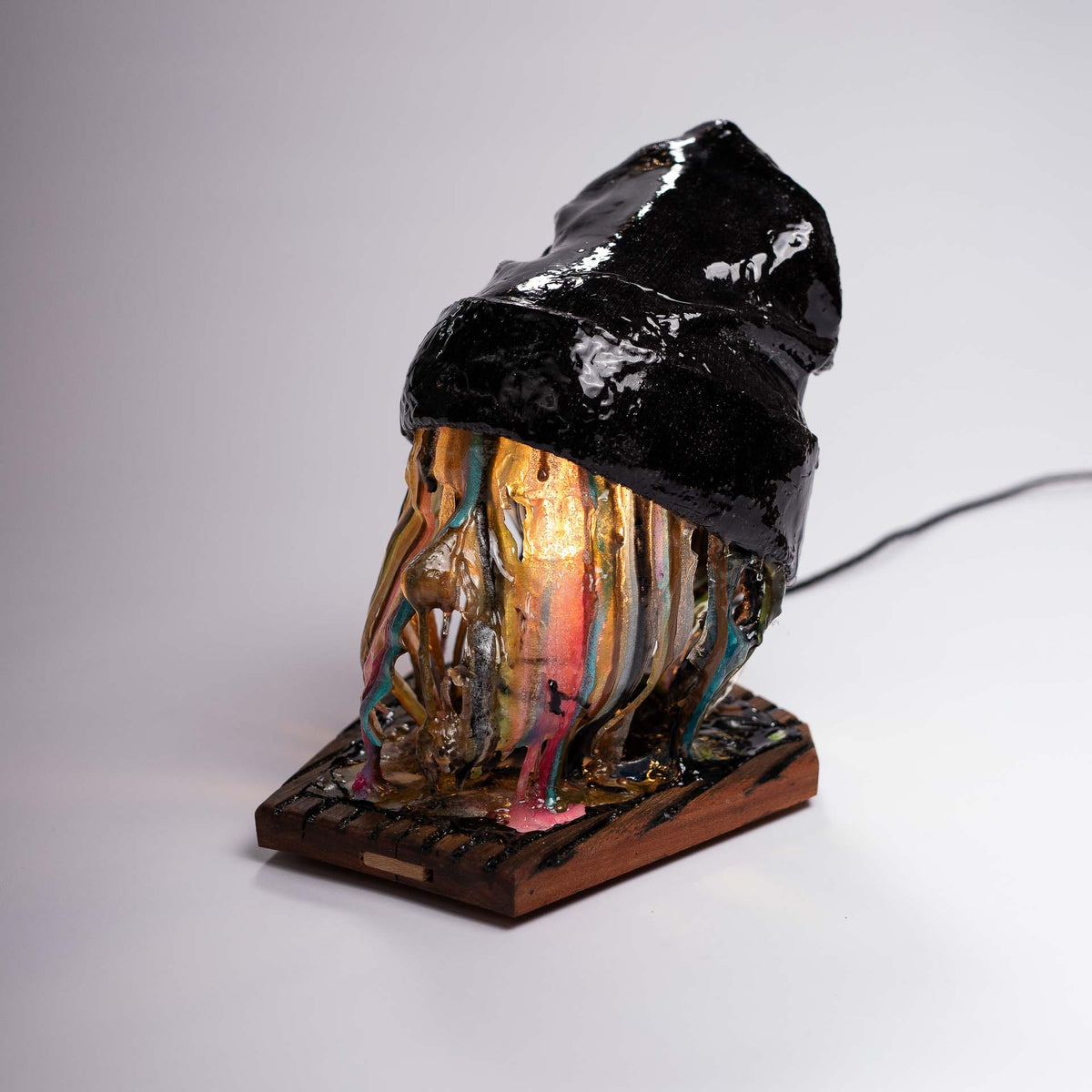 Melting Sahne sculpture, three-quarter view showing the resin drips and the wooden base