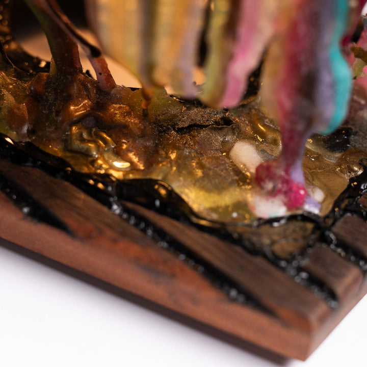 Detail of the epoxy resin pooling on the dark wooden base with pink and turquoise drips